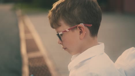 schoolboy-draws-in-paper-notebook-sitting-on-brown-bench