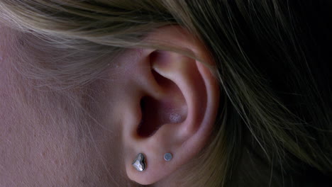 close-up macro of the ear of a young woman with two earrings