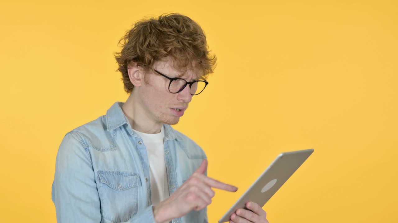 Redhead Young Man Loss on Tablet, Yellow Background