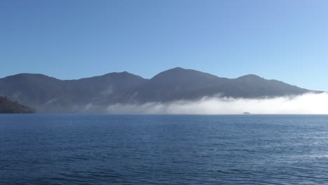 boat passing through early-morning low cloud above a calm sea in summertime