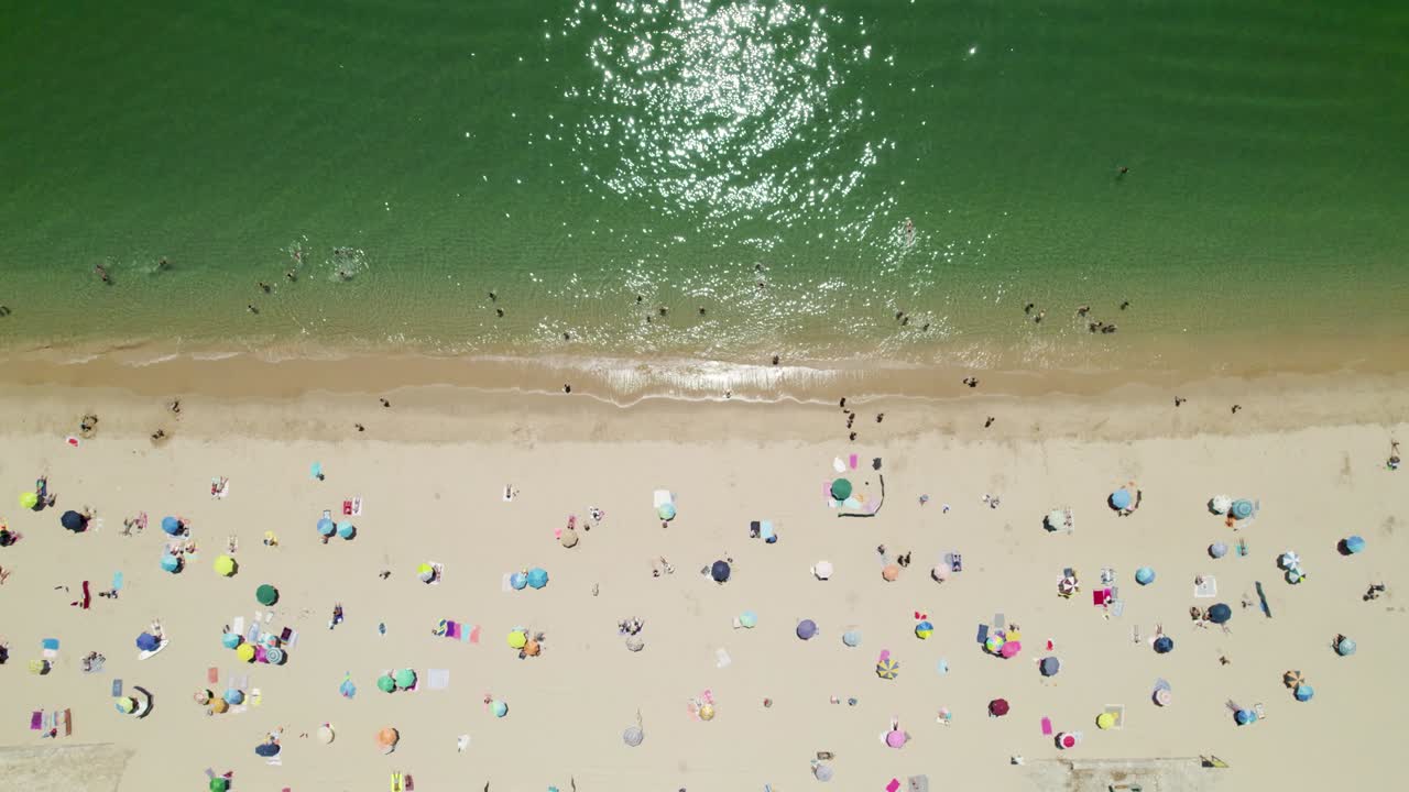 다채로운 파라솔과 포르투갈 세심브라의 해변에서 휴식을 취하는 사람들