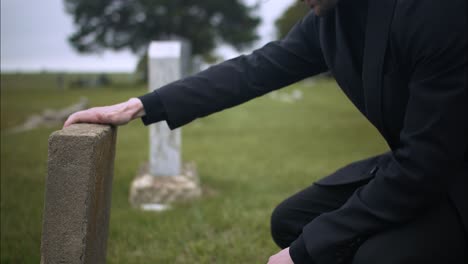 sad, emotional man in cemetery grieving over death of loved one