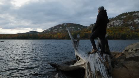 man in black coat enjoys beautiful fall sunset mountain view, wide pan