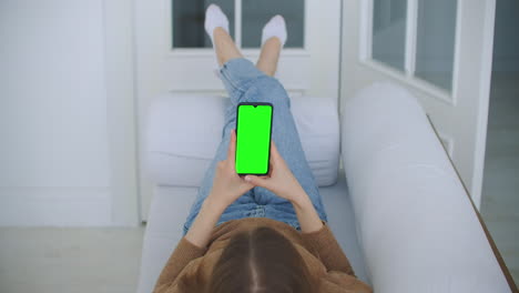 Nahaufnahme-Eines-Greenscreen-Vorlagen-Smartphones-In-Frauenhänden-Zu-Hause.-Mädchen-Schaut-Sich-Inhalte-An,-Ohne-Den-Gadget-Bildschirm-Zu-Berühren.-Modernes-Technologie--Und-Informationskonzept.