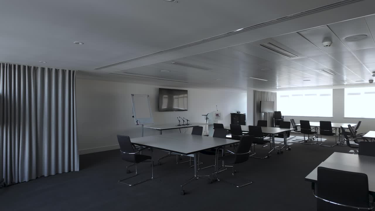 A panoramic view of the empty boardroom or conference room, adorned with chairs and tables, pan left shot