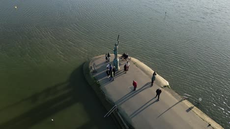 sightseers at the promenade with the monument of byrhtnoth in maldon, essex, united kingdom