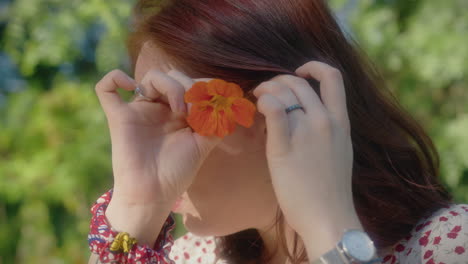 woman puts an orange flower behind her left ear