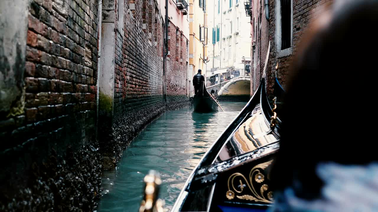 Vista trasera de una mujer mayor disfrutando de un hermoso paseo en góndola por un estrecho canal de Venecia durante sus vacaciones de jubilación.