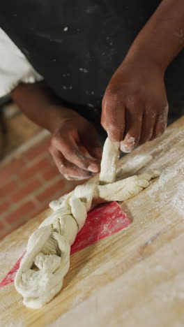 video vertical de un panadero afroamericano preparando la masa en una panadería