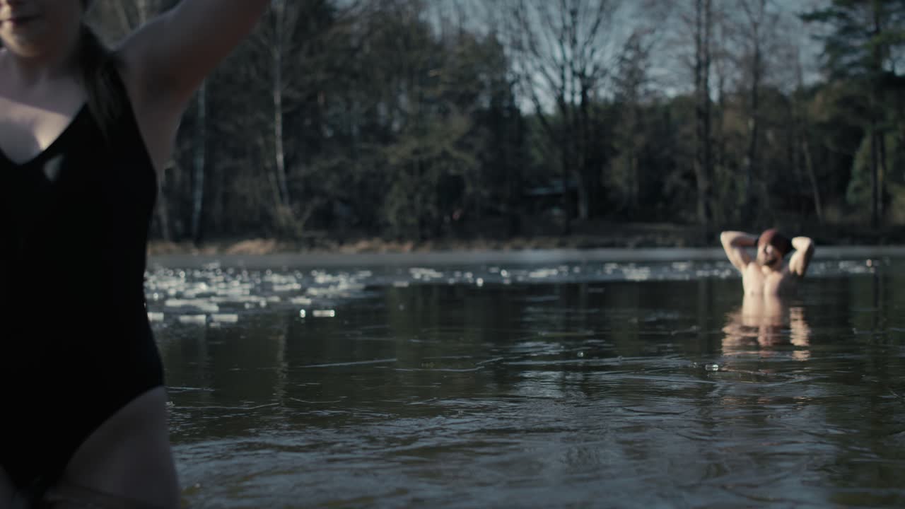 얼어붙은 호수에서 수영하는 백인 커플.