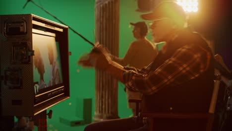 director looks at display controls shooting period drama movie, celebrates successful scene. green screen cgi scene with actors wearing renaissance costumes. crew shooting high budget movie. side view