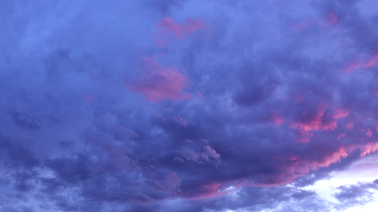 Dramatic deep blue and purple clouds with vibrant pink highlights during a beautiful sunset sky