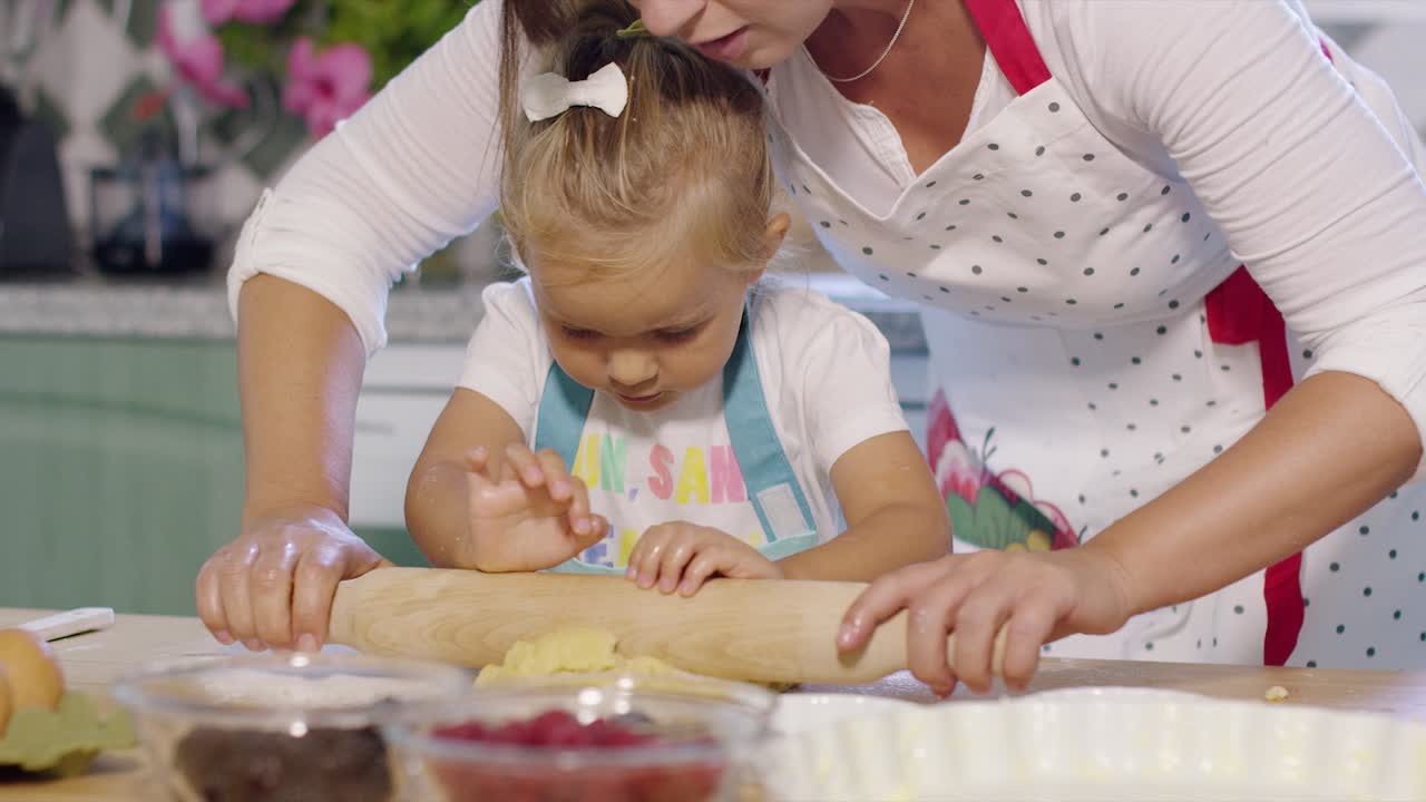 Mother rolling out pastry with a little helper