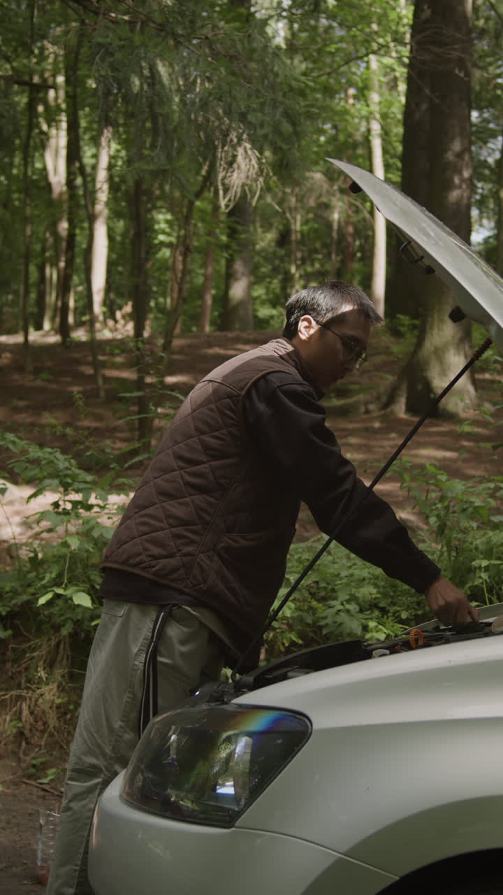 Man inspecting car engine in forest