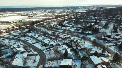 Winter-aerial-view-of-snow-covered-homes-and-factories-in-a-suburban-neighborhood-in-Oakville,-Ontario,-Canada