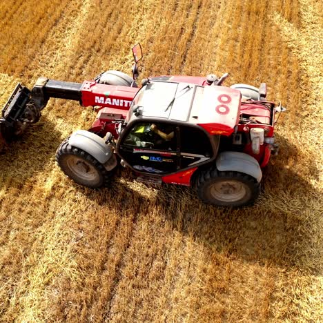 tractor collects hay on the field. farmers collect haystacks and put them on tractor trailer