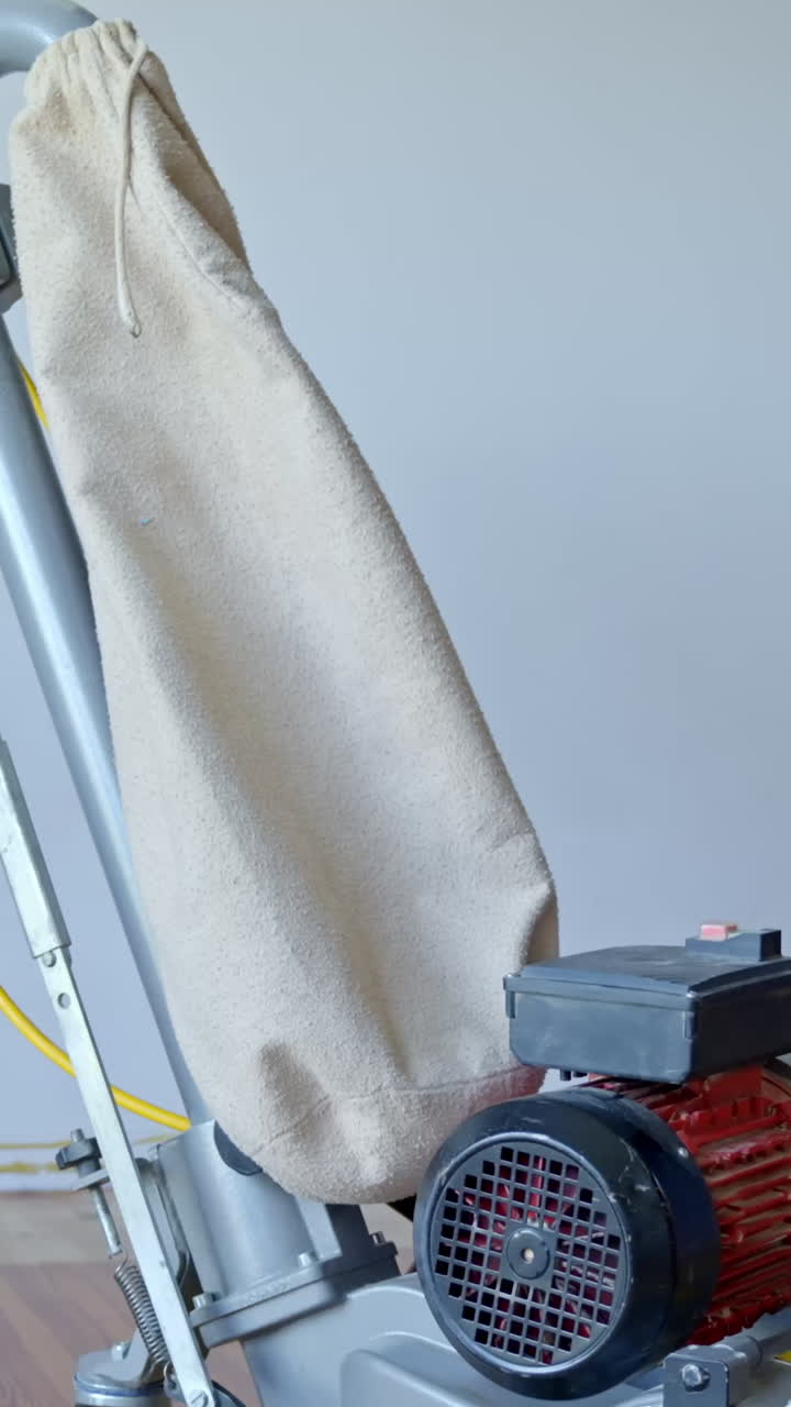 Close-up vertical view of sanding equipment working on a wood floor during refinishing.