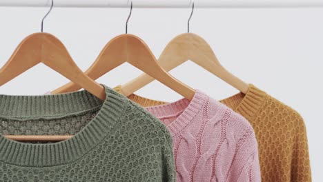 Video-of-three-multi-coloured-sweaters-on-hangers-and-copy-space-on-white-background