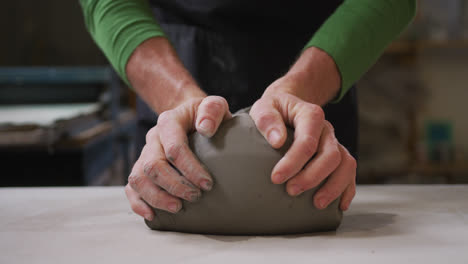 close up view of male potter kneading the clay at pottery studio