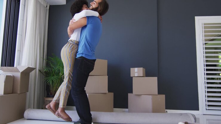 Mixed race couple dancing together in between cardboard boxes at new apartment house