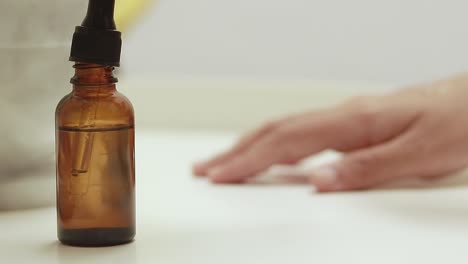 focus to a brown glass bottle dropper containing serum product and testing it, showing skincare routine, health and wellness