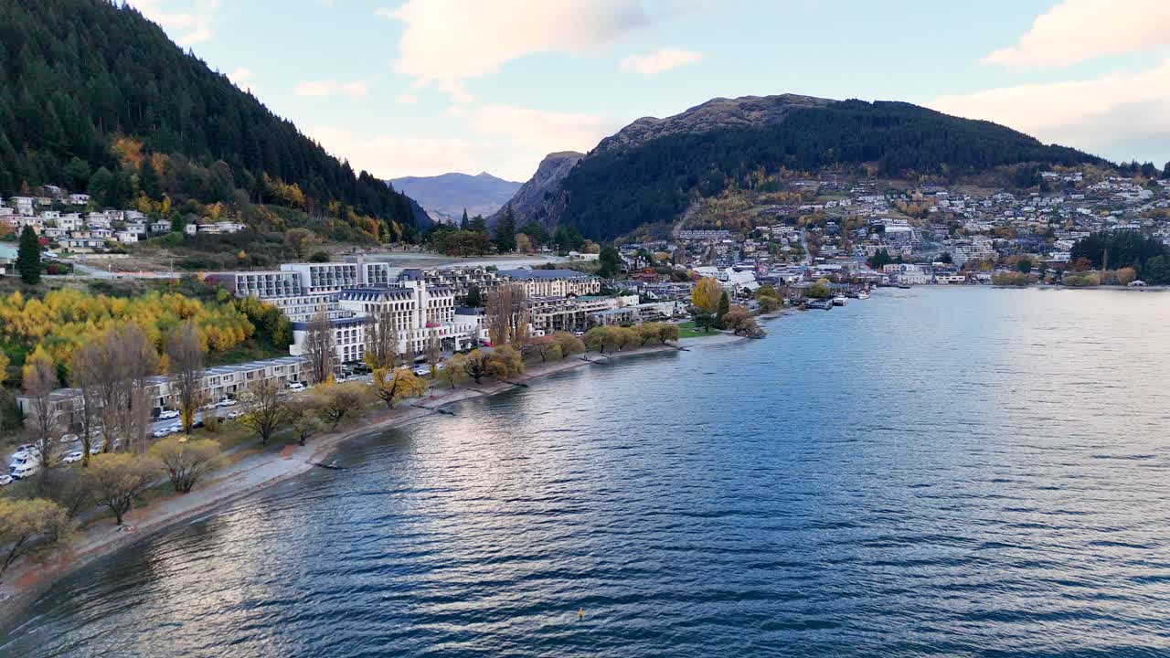 Aerial footage captures Queenstown's scenic landscape and Lake Wakatipu under soft daylight, showcasing natural beauty and urban charm