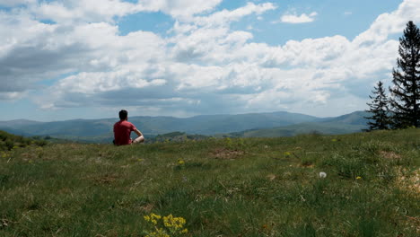 a man sitting on the grass in a mountain