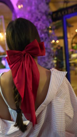 young woman with red bow at night