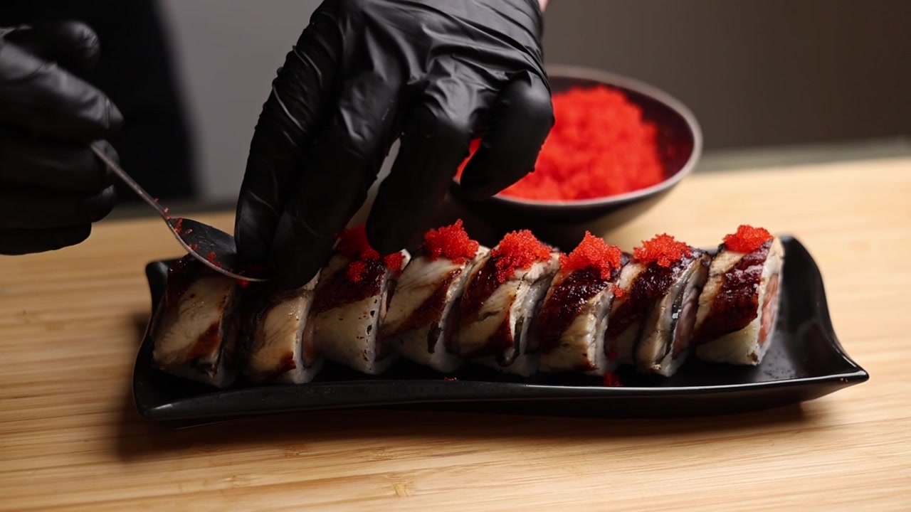 Chef che guarnisce roll di sushi freschi con tobiko rosso