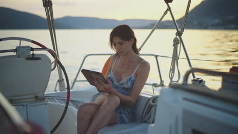 woman relaxing with a tablet on a yacht at sunset