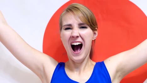 japanese young woman celebrating while holding the japanese flag in slow motion