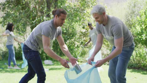 two caucasian young male volunteers collecting plastic material in a bag and high fiving each other