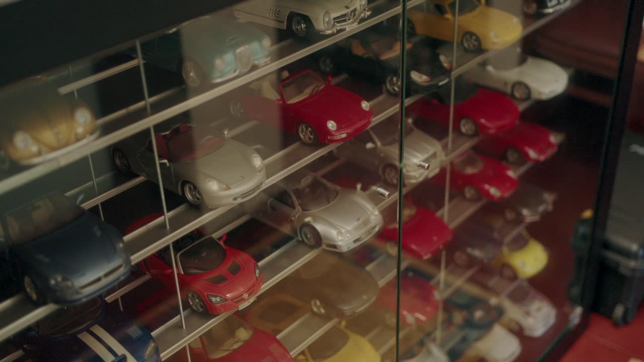 Shelves filled with detailed collectible model cars behind a glass display case