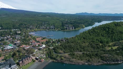 panoramic drone view over pucón, chile showing lakeside town, lush hills, and distant lake horizon under a clear sky