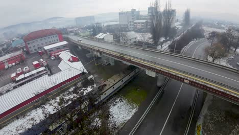 Zug-Fährt-An-Einem-Bewölkten,-Nebligen-Tag-In-Einer-Osteuropäischen-Industriestadt-Unter-Einer-Brücke-Hindurch