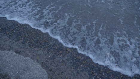 pan of waves rolling onto the gravel shore