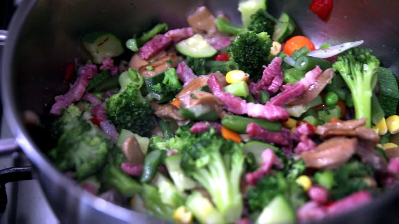 여러 가지 색의 야채와 베이컨을 채운 냄비를 가스렌지 위에 놓고 끓이는 슬라이드 샷