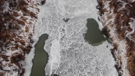 serene winter landscape, frozen river on cold day, aerial top down