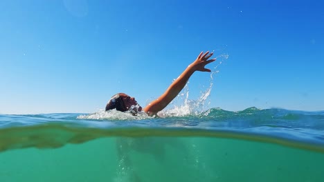 Split-underwater-view-of-little-child-girl-learning-to-swim