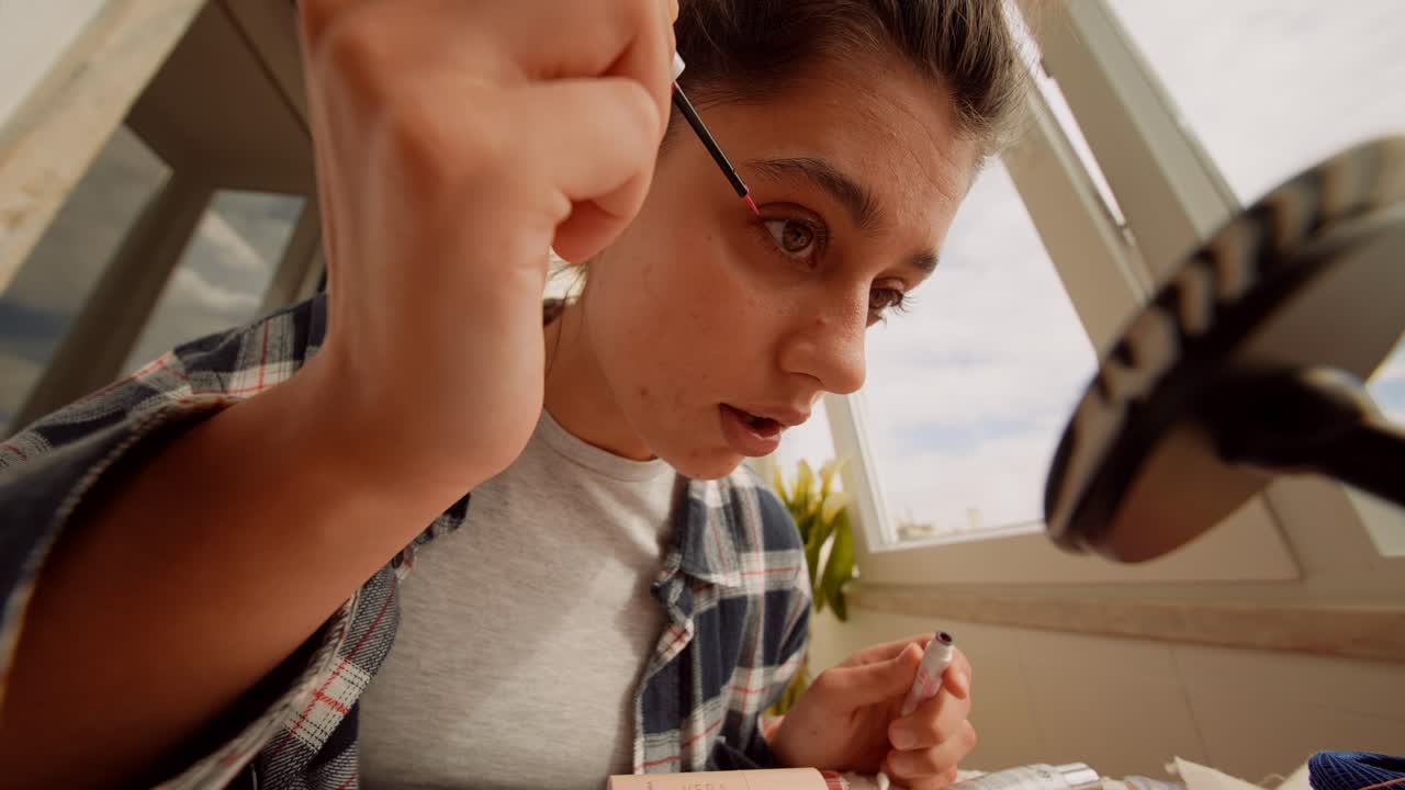 Giovane donna che applica l'eyeliner mentre si guarda allo specchio.