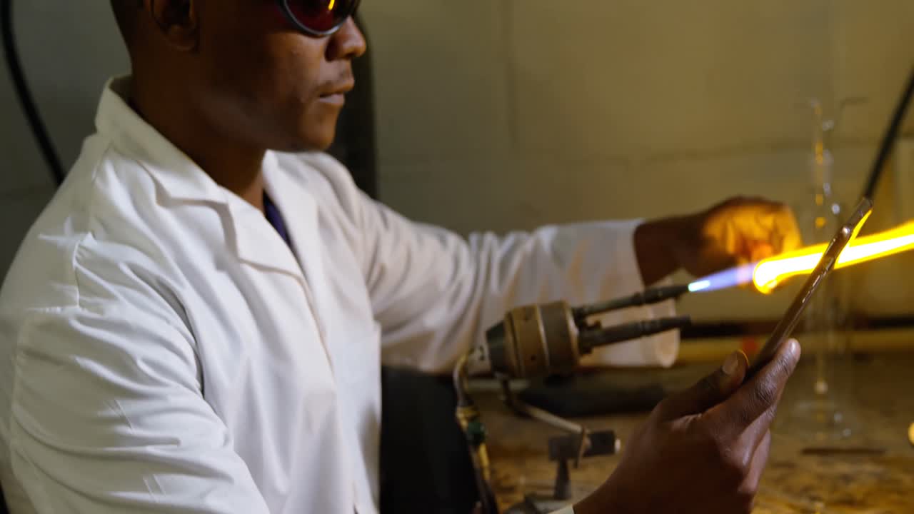 유리 공장에서 유리를  ⁇ 는 흑인 남성 노동자의 측면 보기 4k