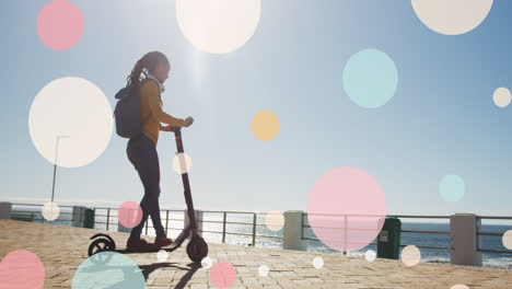 Animación-De-Puntos-En-Movimiento-Sobre-Una-Mujer-Birracial-Montando-Una-Scooter-En-El-Paseo-Marítimo