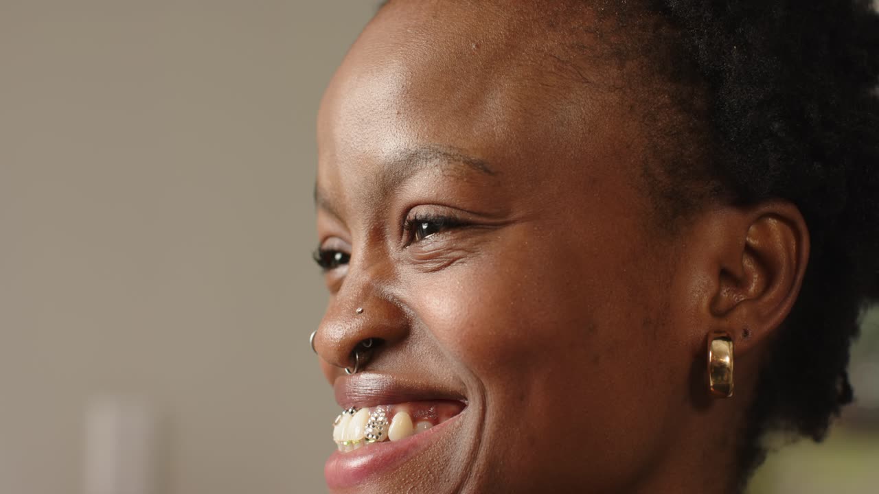 Su richiesta, donna afroamericana che trasforma il sorriso in un ghigno, mostrando apparecchio ortodontico, piercing e orecchini alla finestra