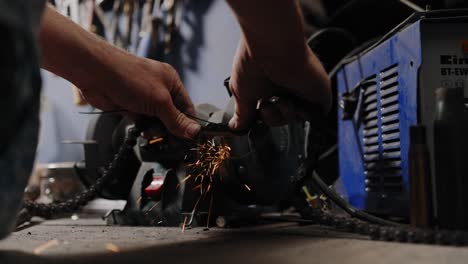 Close-up-shot-of-mechanic-breaking-a-chain-open-with-a-whetstone