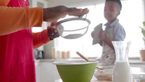 Feliz-Abuelo-Y-Nieto-Afroamericano-Horneando-En-La-Cocina,-Cámara-Lenta