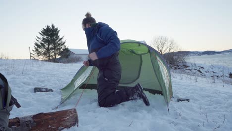 man assembling tent on snowy ground at wintertime in norway