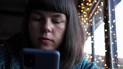 burnette girl with bangs using her phone for messaging