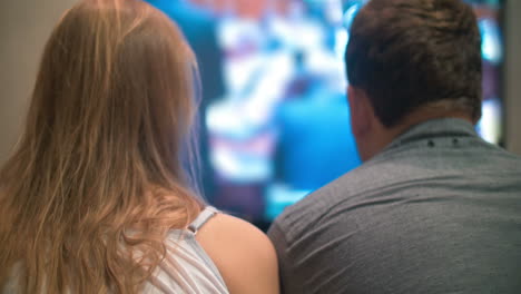 young man and woman watching television at home