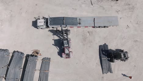 drone top shot of forklifts and labour loading steel to be exported by ship