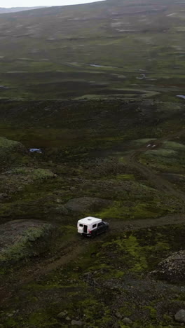 vertical drone shot around a camper truck, driving in the wilderness of iceland